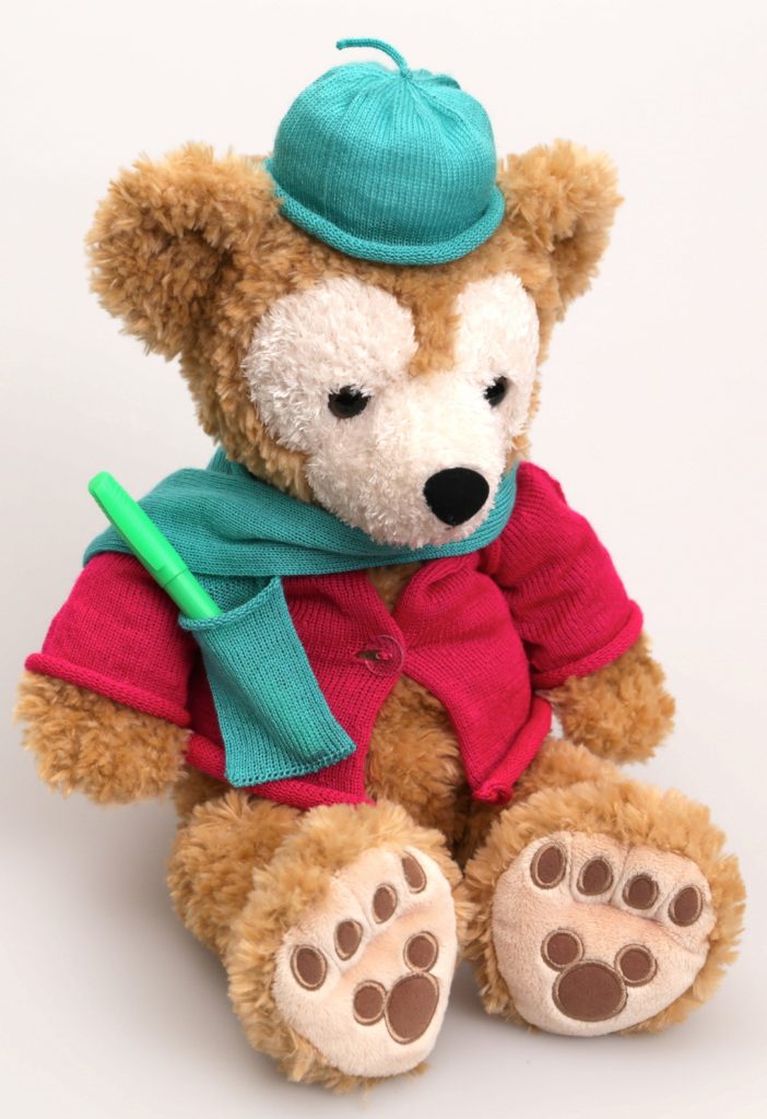 A teddy bear wearing a knit hat, scarf (with pocket) and sweater