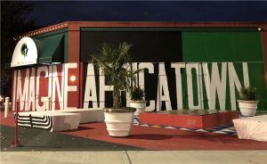 Picture of potted plants and a bench with the word Africatown in the background, painted in bright red and green colors